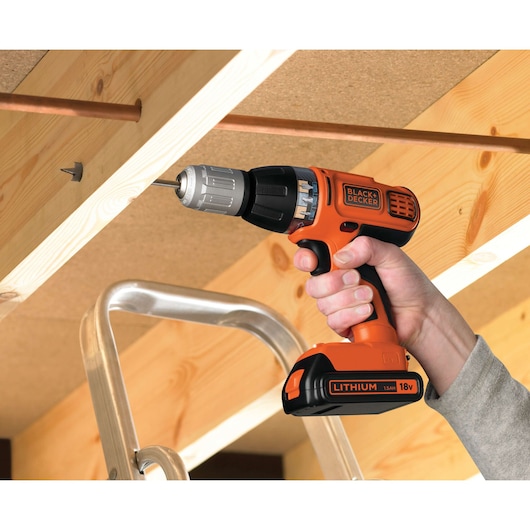 BLACK+DECKER ASL188K cordless drill in use, orange and black body, 18V Lithium, drilling into wood.