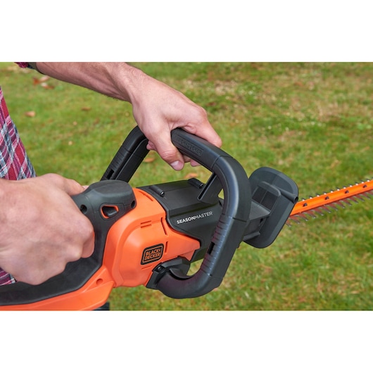 BLACKDECKER BCASK81D hedge trimmer being operated outdoors, close-up of handle and blade.