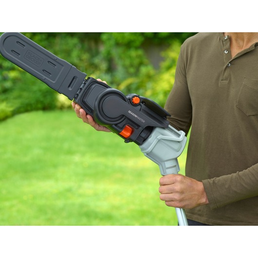 BLACKDECKER BCASK861D garden tool with chainsaw attachment and blade cover held outdoors.