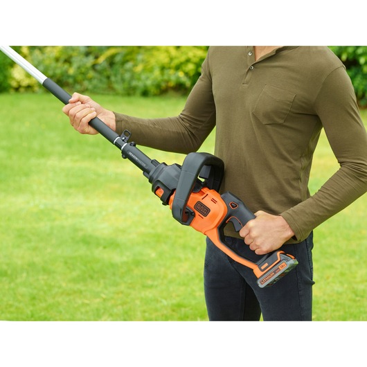 BLACK+DECKER BCASK861D cordless orange and black garden multi-tool held by person outdoors.