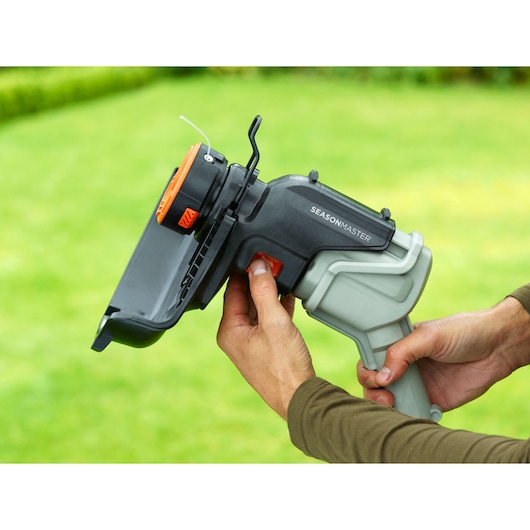 BLACKDECKER BCASK891D garden tool handle with orange and black trimmer head, close-up in outdoor setting.