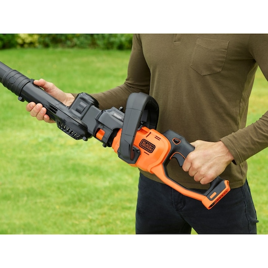 Photo of a person holding a BLACK+DECKER BCASK8967D2 orange and black cordless garden tool outdoors.