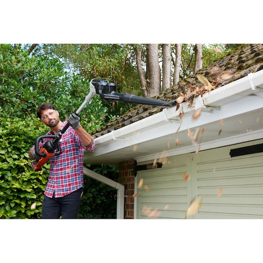 BLACKDECKER BCASK8967D2 garden blower clearing leaves from a house gutter outdoors.