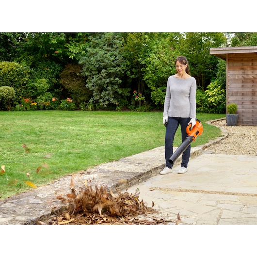 BLACKDECKER BCBL200L leaf blower in use clearing leaves on patio in garden.