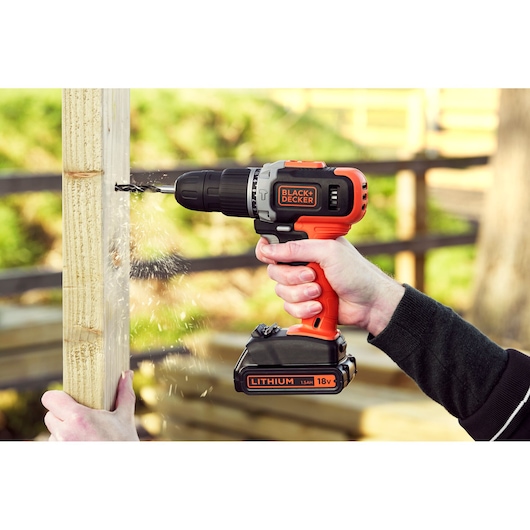 BLACKDECKER BCD003C1C cordless drill with 18V lithium battery drilling into wood outdoors.