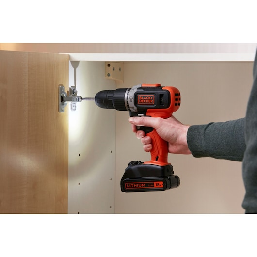 BLACKDECKER BCD003C1C cordless drill in use assembling cabinet, orange and black color, photography closeup