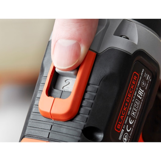Close-up photo of hand adjusting speed switch on BLACK+DECKER BCD003C1C cordless drill, showing speed setting 2.
