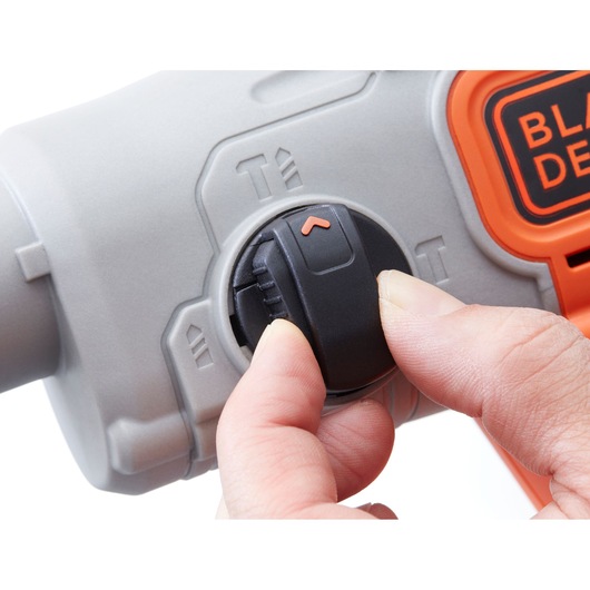 Close-up photo of a hand adjusting BLACKDECKER BCD900D1S mode selector switch with orange accents on grey tool body.