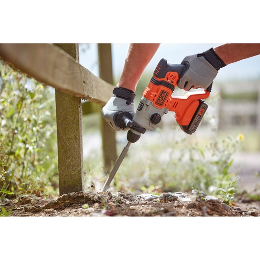 BLACKDECKER BCD900E2K cordless rotary hammer used outdoors, person wearing gloves breaking ground.