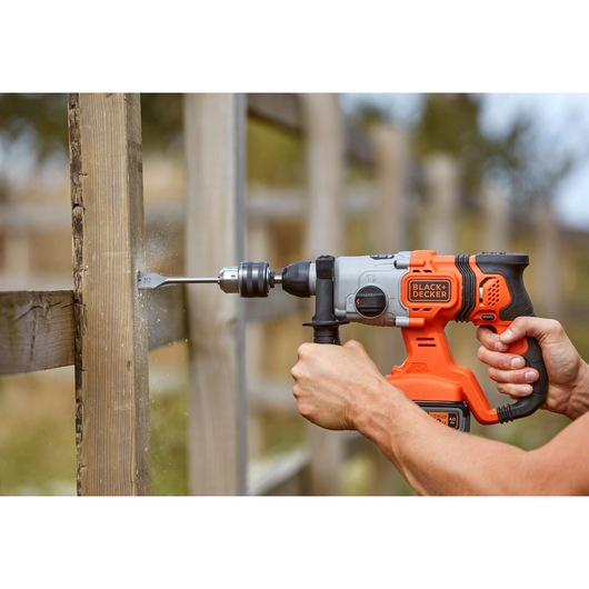 Photo of BLACK+DECKER BCD900M1K cordless hammer drill being used to drill a hole in an outdoor wooden post.