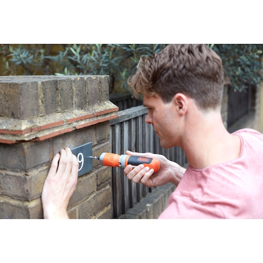 BLACKDECKER BCF602C cordless screwdriver used to attach a house number plate to a brick wall.