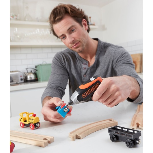 BLACK+DECKER BCF611CK cordless screwdriver used to assemble toy train parts on a kitchen table.
