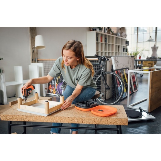 BLACKDECKER BCF611CK cordless screwdriver used for assembling wooden furniture in a modern room.