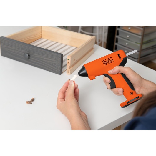 Photo of BLACKDECKER BCGL115OB cordless glue gun being used in woodworking with a drawer on a white table.