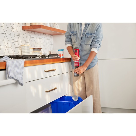 BLACKDECKER BCKM1012KR handheld can opener used in a modern kitchen near a recycling bin.