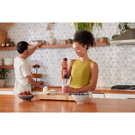 Photo of BLACKDECKER BCKM1012KR hand blender being used to mix smoothie in a kitchen with fruits on counter.