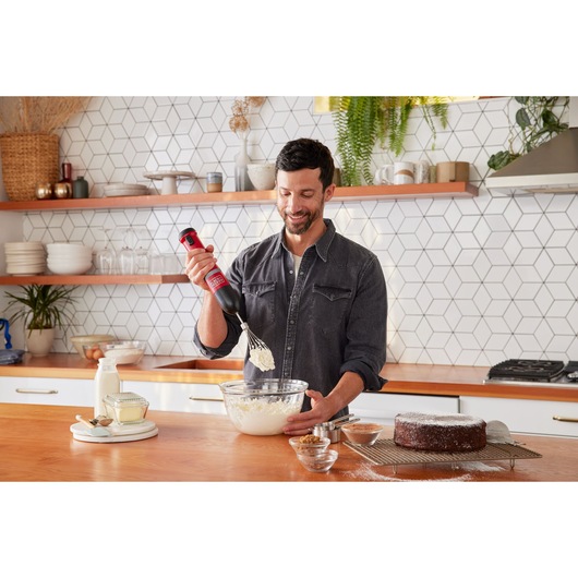 BLACKDECKER BCKM1012KR hand mixer used for whipping ingredients in a glass bowl, modern kitchen setting.