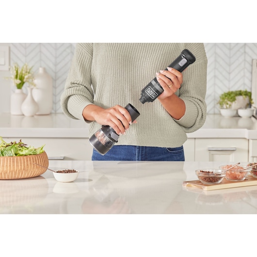 Photo of BLACKDECKER BCKM1016KSB electric spice grinder held in hand in modern kitchen setting.