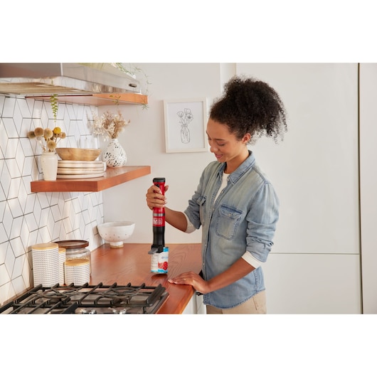 BLACKDECKER BCKM1016KSR red electric jar opener in use on kitchen counter, product photography.
