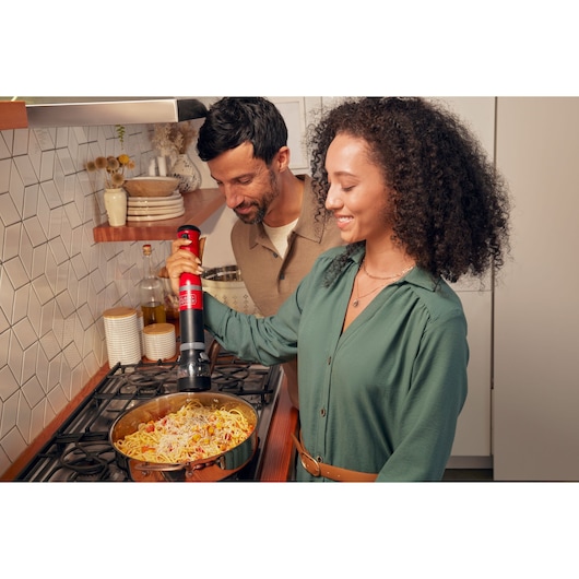BLACKDECKER BCKM1016KSR cordless kitchen tool in red used to prepare pasta in a pan on stove.