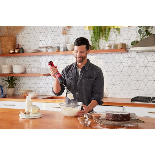 BLACKDECKER BCKM1016KSR hand mixer in use in a kitchen, mixing batter in a glass bowl.
