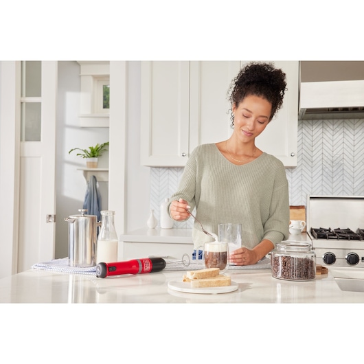 Photo of BLACKDECKER BCKM1016KSR handheld milk frother on kitchen counter near coffee, bread, and glass jar of beans.
