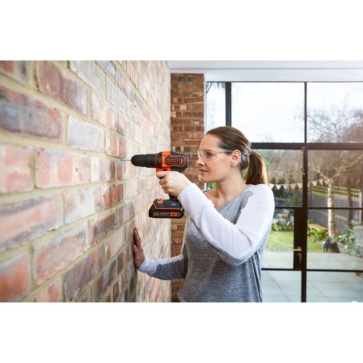 BLACKDECKER BCKSB04 cordless drill in use on brick wall indoors.