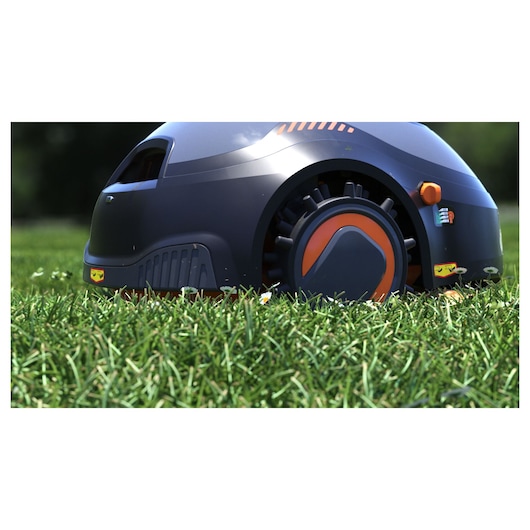 BLACKDECKER BCRMW123 robotic lawn mower with orange accents on grass, close side view.