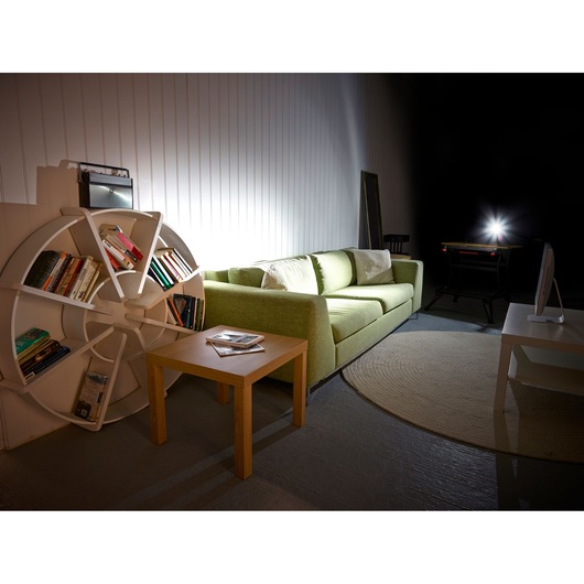 BLACKDECKER BDCCF12N cordless LED work light illuminating modern living room with green sofa and bookshelf.