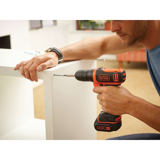 BLACKDECKER BDCD12 cordless drill used to assemble white furniture, close-up of product in use.