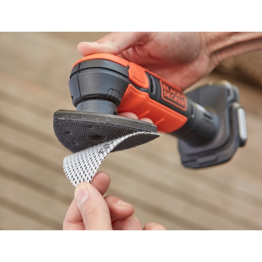BLACK+DECKER BDCDS12N cordless detail sander in use, close-up showing sanding pad being attached.