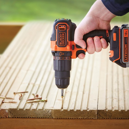 Photo of BLACK+DECKER BDCHD18K1B2 cordless drill driving screw into wooden board, visible screws nearby.