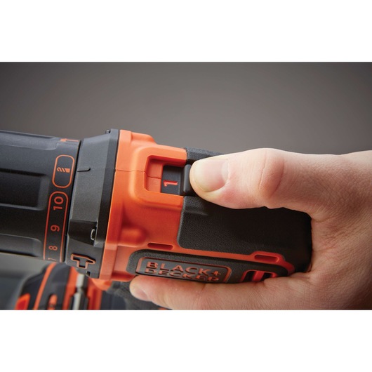 Close-up of hand adjusting BLACKDECKER BDCHD18K1B2 cordless drill speed setting, black and orange detail.