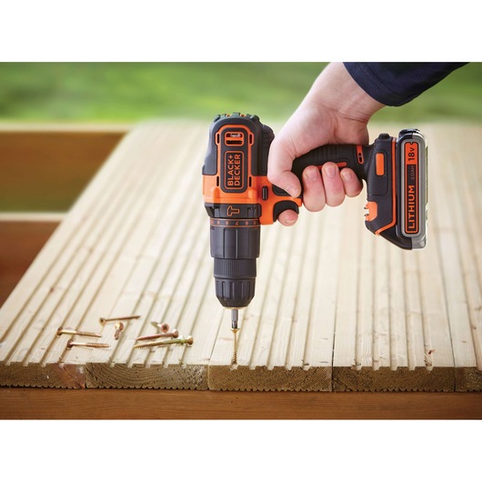 BLACKDECKER BDCHD18KB2 cordless drill, orange-black, being used to drive screws into wooden planks.