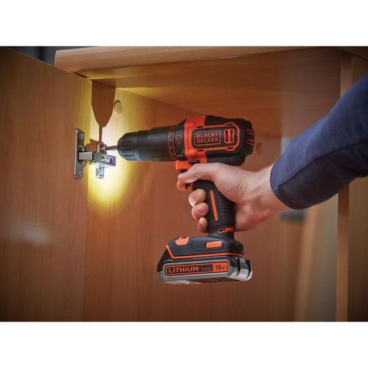 BLACK+DECKER BDCHD18KB2 cordless drill being used to install a hinge on a wooden cabinet.