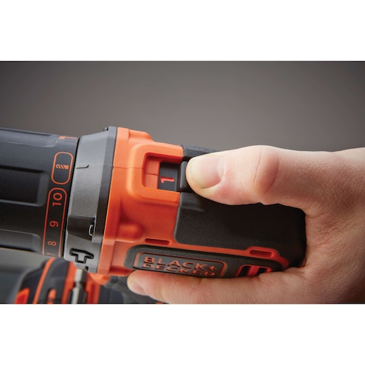Close-up of a hand adjusting the settings on a BLACK+DECKER cordless drill, highlighting the speed control switch and part of the handle.