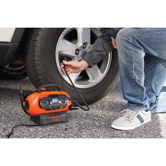 BLACKDECKER BDCINF18N orange portable air compressor inflating car tire, photography in outdoor setting.