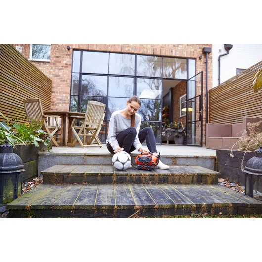 BLACKDECKER BDCINF18N inflator and soccer ball on garden steps, person sitting outdoors, patio in background.