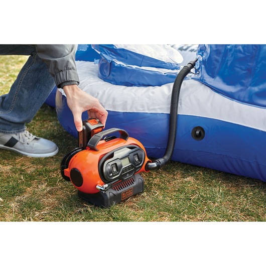 Photo of BLACKDECKER BDCINF18N portable inflator in use inflating a blue inflatable on grass.