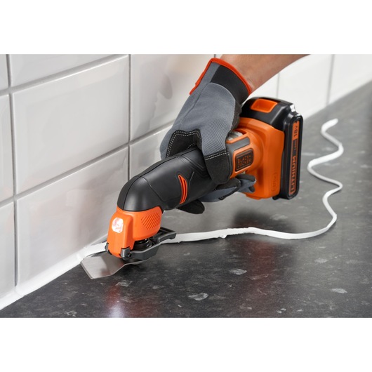 Photo of BLACKDECKER cordless oscillating tool BDCOS18N used to remove sealant from tiled countertop corner.