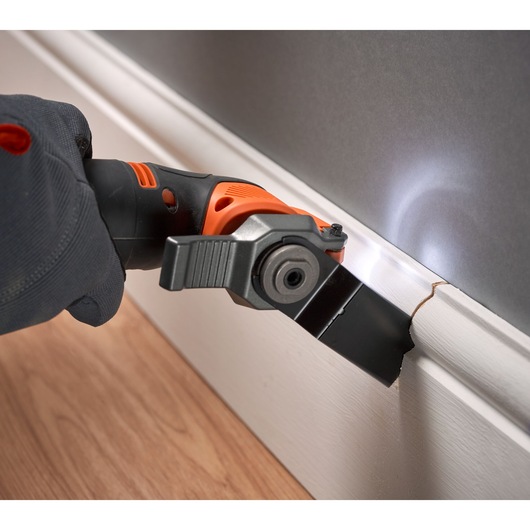 BLACKDECKER BDCOS18N oscillating tool cutting white baseboard with LED light, close-up action.