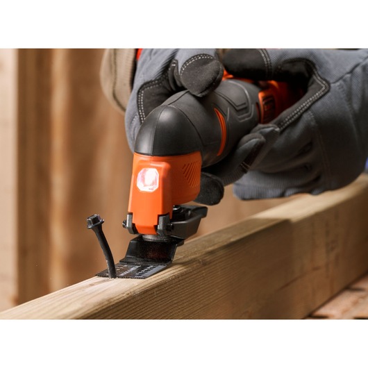 BLACKDECKER BDCOS18N oscillating multi tool cutting wood, close-up with gloved hand, construction setting.