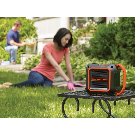 BLACK+DECKER BDCSP18N portable speaker with orange accents on a metal table outdoors.