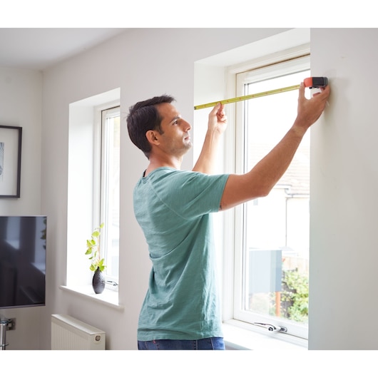 BLACKDECKER BDHT84002 tape measure in use measuring window width indoors.