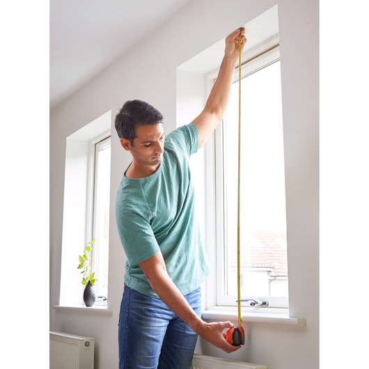 BLACKDECKER BDHT84002 tape measure used to measure window height indoors.