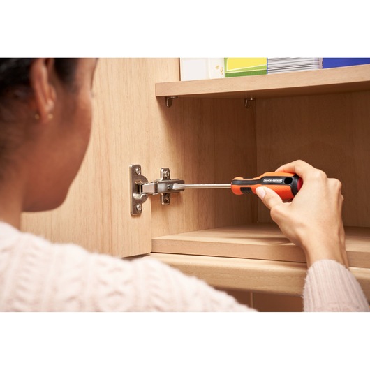 BLACKDECKER screwdriver BDHT84014 used to adjust cabinet hinge in woodworking setting.