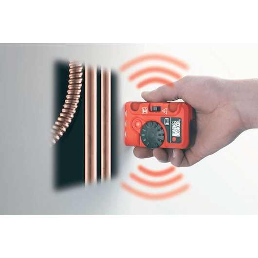 Photo of BLACKDECKER BDS200 stud detector in hand, scanning wall to reveal copper pipes.