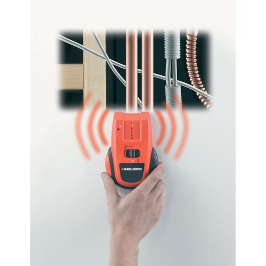 BLACK+DECKER BDS300 stud and pipe finder held on wall, showing detection signals and pipes behind surface.
