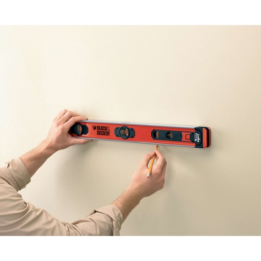 Photo of BLACKDECKER BDSL30 level tool held against wall, person marking with pencil.