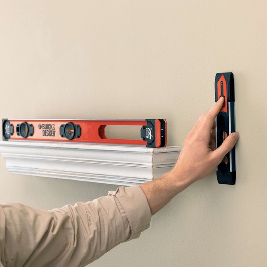 BLACKDECKER BDSL30 level tool used against a beige wall, photo shows hand holding the tool above a white shelf.